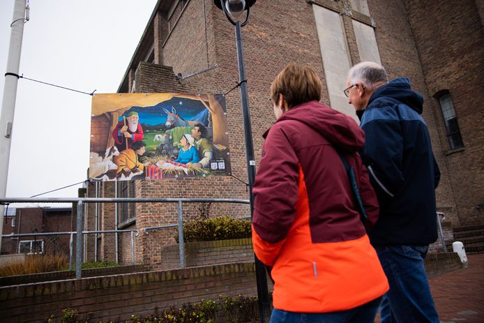 Voorbijgangers bekijken een kerstkunstwerk dat in Oostburg hangt.