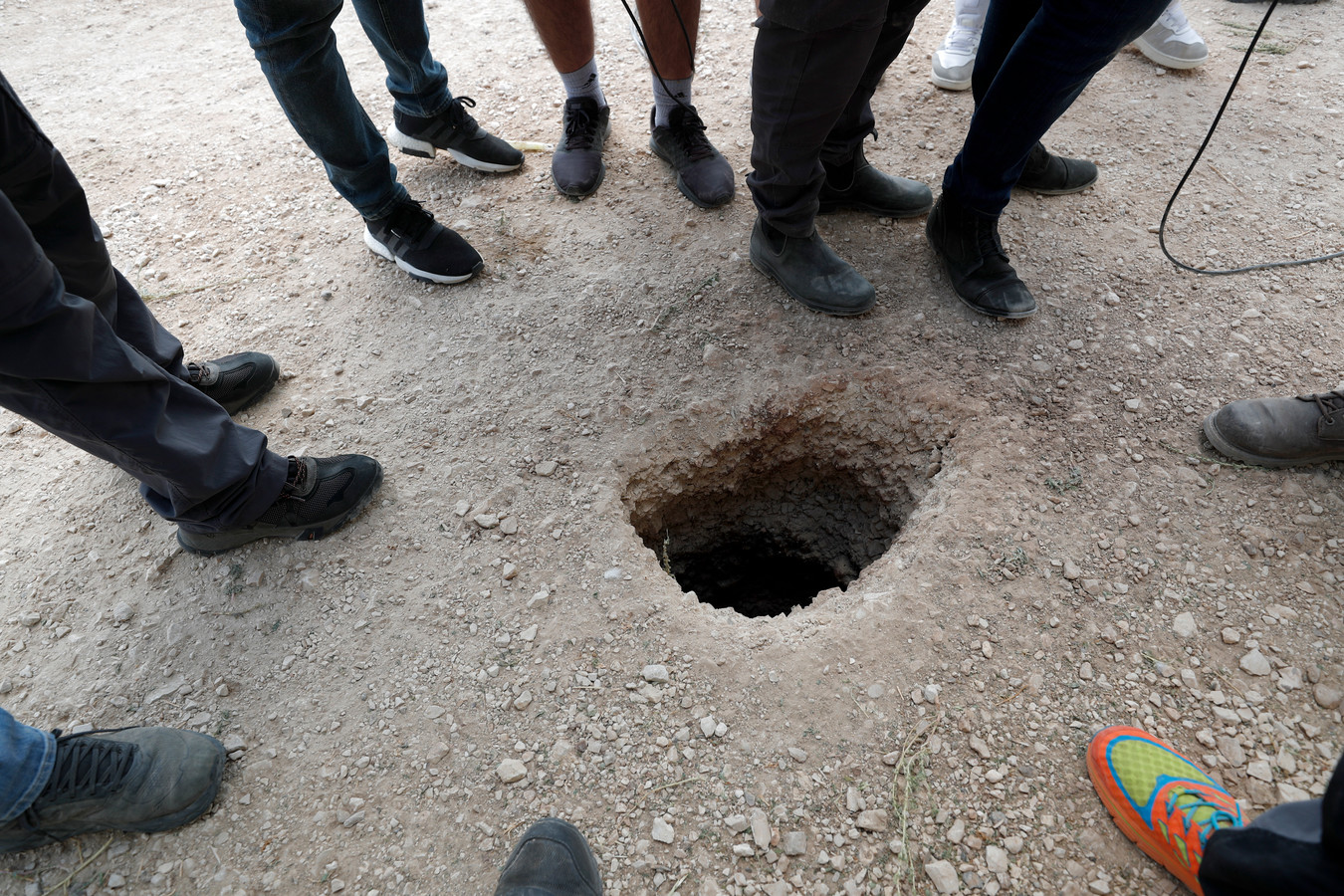 Des personnes se tiennent près d’un trou dans le sol à l’extérieur des murs de la prison de Gilboa après que six militants palestiniens s’en soient échappés, dans le nord d’Israël, le 6 septembre 2021.