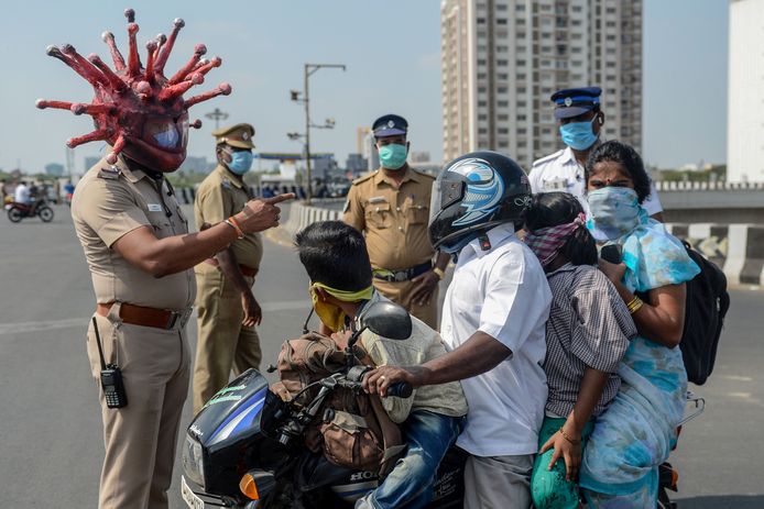 Een politieagent met 'coronahelm' in Chennai (India) spreekt een gezin toe . India is in lockdown.