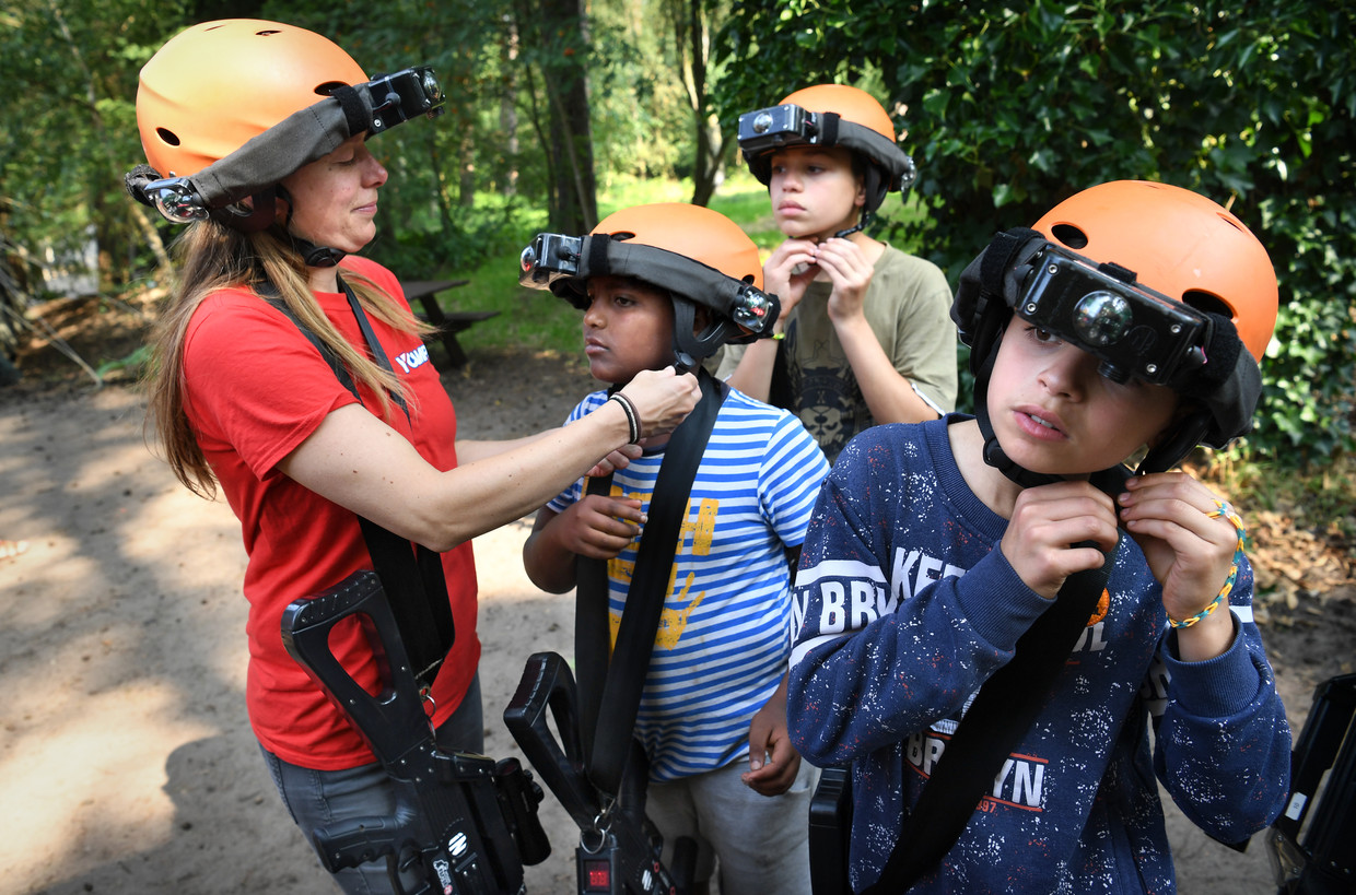Vrijwilliger Mieke Visch helpt kinderen hun helm op doen voor het lasergamen tijdens de vakantieweek voor vluchtelingenkinderen.  Beeld Marcel van den Bergh / de Volkskrant