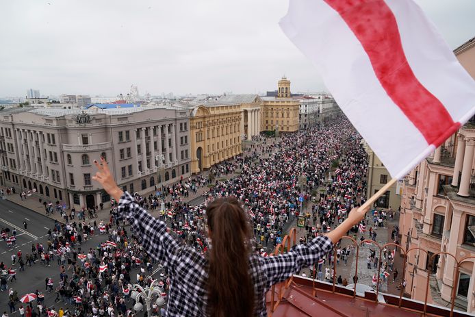 Een vrouw zwaait met een oude Belarussische vlag tijdens de protesten in augsutus vorig jaar, na de verkiezingen. Loekasjenko reageerde met harde hand op de protesten. Zo’n 30.000 vreedzame Belarussen werden gearresteerd, afgevoerd en gemarteld.. (AP Photo/Evgeniy Maloletka)