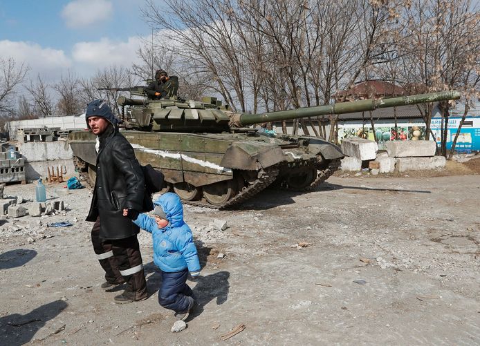 Een vader loopt met zijn kind langs een tank van pro-Russische strijders