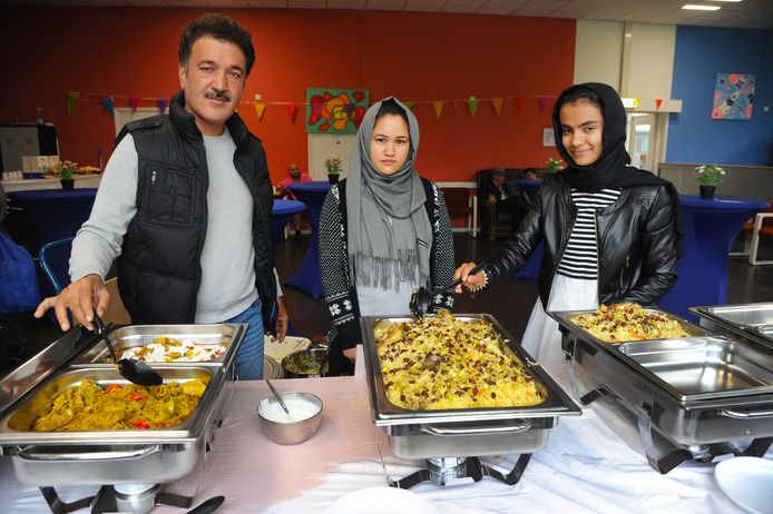 Fawad Qasemi, Nazira Alizada en Mamin Azizi (vlnr) presenteren grote schalen zelfgemaakte, Afghaanse maaltijden.