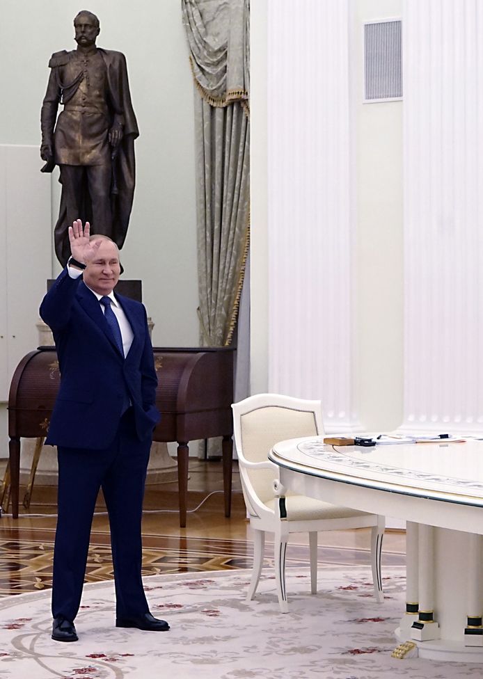 Een foto die minder vaak de kranten haalde: Poetin die tijdens de ontmoeting vrolijk naar Macron zwaait, die naar we aannemen al aan de andere kant van de lange tafel zit, meters verderop.