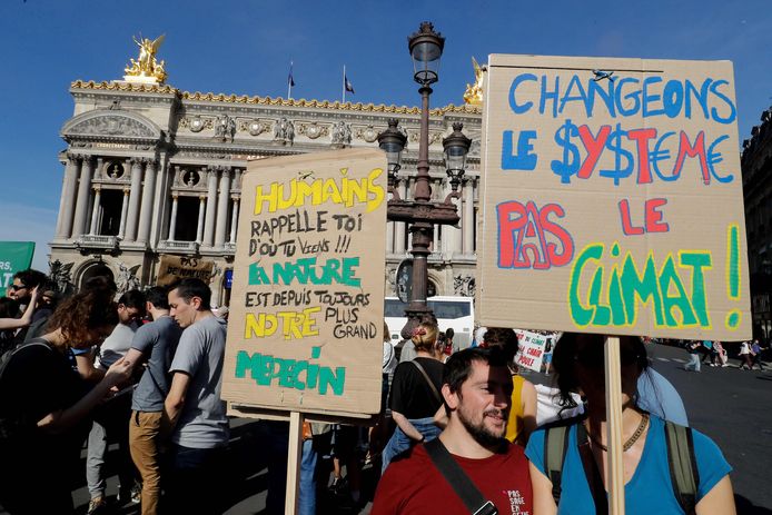 Protestborden met de tekst: "Mensen herinner u waar we vandaan komen! De natuur is sinds ons bestaan ons grootste medicijn" en "Verander het systeem, niet het klimaat".