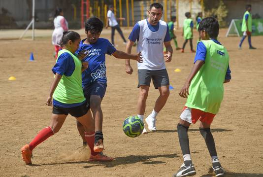 Xavi Hernández (midden) voetbalt met kinderen in Mumbai.