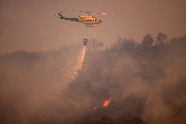 Een blushelikopter probeert het vuur te doven in de bergen van Sierra de Mijas in het Spaanse Málaga. Beeld Jorge Guerrero / AFP