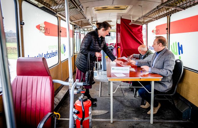 Na inlevering van haar stempas in het mobiele stembureau, ontvangt deze kiezer in Zuidzijde haar stembiljet.