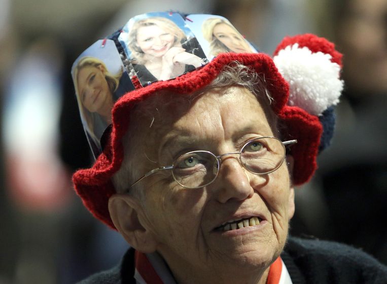 Een vrouw met een hoed met daarop afbeeldingen van FN-frontvrouwen Marine le Pen en Marion Marechal Le Pen Beeld ap