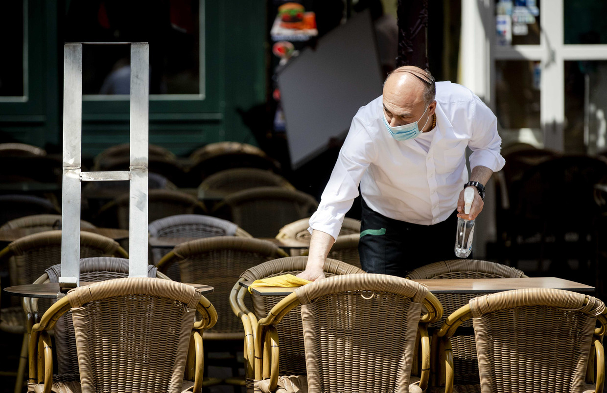 Een medewerker desinfecteert een tafel op een terras aan het Rembrandtplein in Amsterdam. Beeld ANP