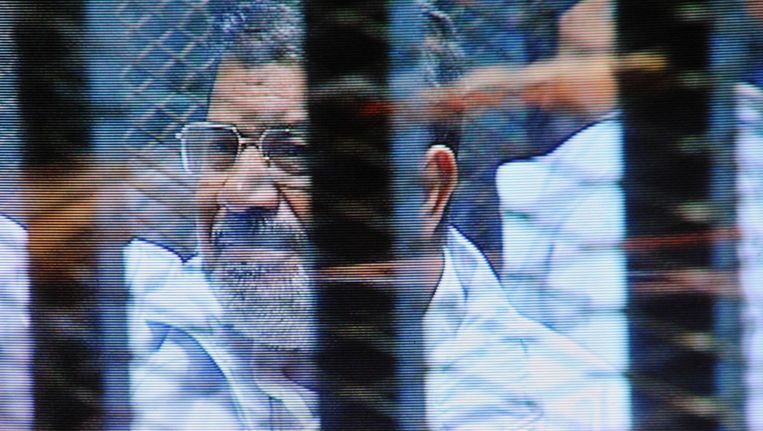 Mohammed Morsi (rechts) staat in een glazen kooi in de rechtbank in Caïro. Beeld ap