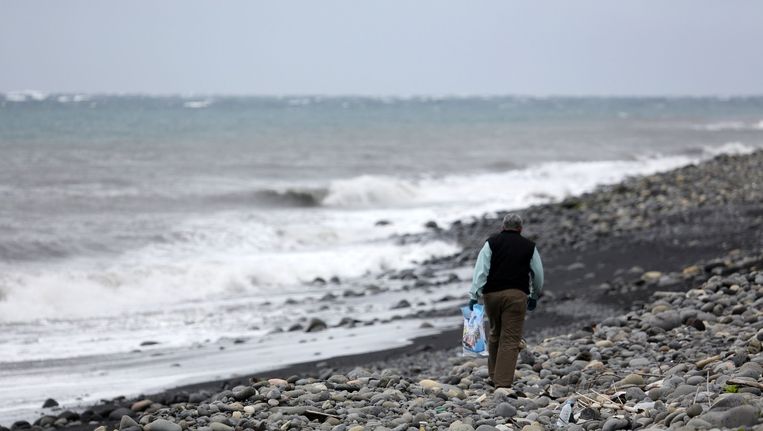 Een Maleisische expert zoekt naar brokstukken van Malaysia Airlines-vlucht MH370 op een strand van het eiland La Réunion. Beeld AFP