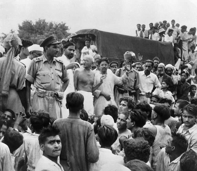 Op de foto, genomen op 22 september 1947, staat Mahatma Gandhi (midden). Hij bezoekt het kamp van moslimvluchtelingen in Purana Qila in New Delhi, terwijl zij zich voorbereiden op hun vertrek naar Pakistan. Beeld ANP / AFP