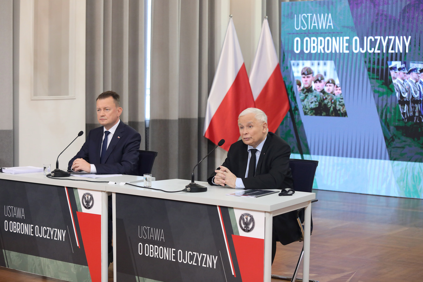 De Poolse minister van Defensie Mariusz Blaszczak (links) en de Poolse vicepremier Jaroslaw Kaczynski (rechts) tijdens de voorstelling van het 'Plan voor de Verdediging van het Vaderland'.