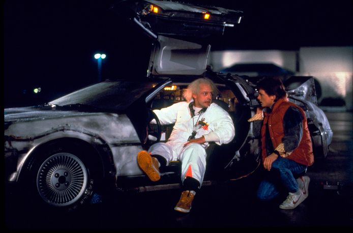 Uitvinder Dr. Emmett ‘Doc’ Brown (Christopher Lloyd) in zijn Delorean-tijdmachine en Marty McFly (Michael J. Fox) in de kaskraker Back To The Future uit 1985.