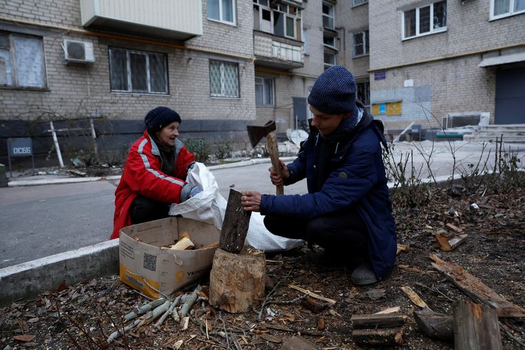 Een man hakt hout van een boom die is omgevallen na een Russische raketaanval, in Bachmoet op 26 december.  Beeld REUTERS