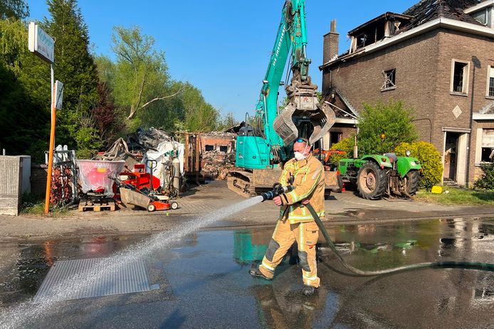 Het door de zware brand ingestorte gebouw van de firma D'Hoker in de Bosstraat in Mere wordt door de brandweer vochtig gehouden om het asbestrisico te beperken.