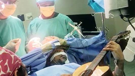 Tijdens de operatie speelt Manzini gitaar en laat de artsen zo weten of alles goed gaat.