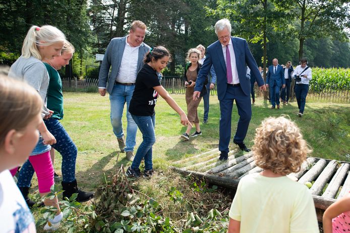Deltacommissaris Peter Glas krijgt op het ‘groenblauwe’ schoolplein bij basisschool Pax Christi in Overdinkel door leerlingen aangewezen waar een kikker zit.