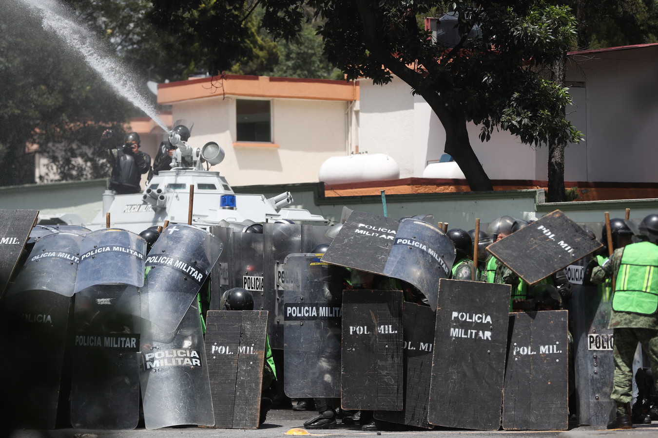 Militaire Politie in Mexico-Stad in cordon rond een waterkanon waarmee geprobeerd wordt de demonstranten uit elkaar te drijven.
