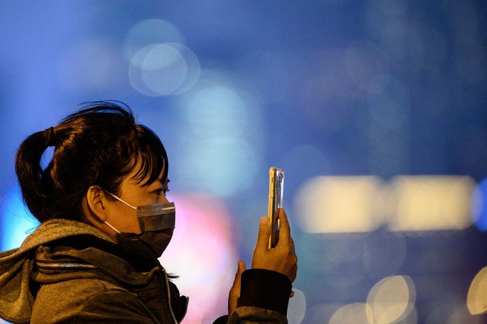 A woman wearing a protective face mask takes photographs near a ferry pier in Hong Kong on February 6, 2020. - China's coronavirus crisis deepened on February 6 with the death toll soaring to 563, as thousands of people trapped on quarantined cruise ships added to the global panic about the epidemic. (Photo by Philip FONG / AFP)