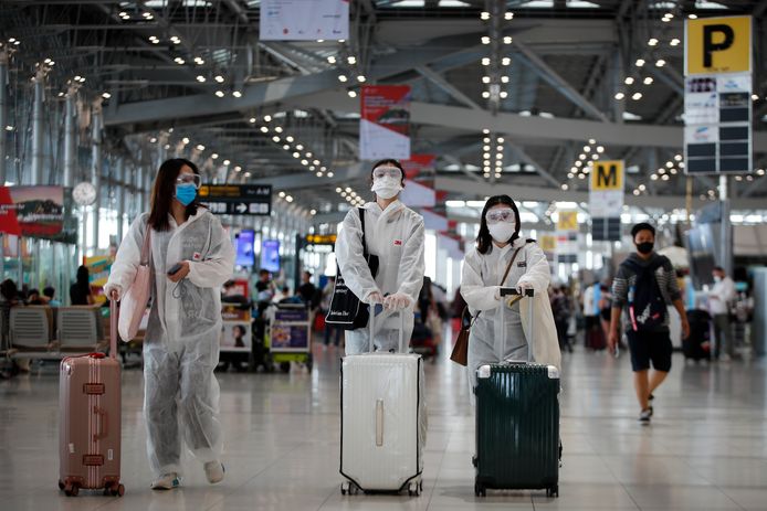 Chinese toeristen dragen mondmaskers en beschermende pakken op de luchthaven van Bangkok.