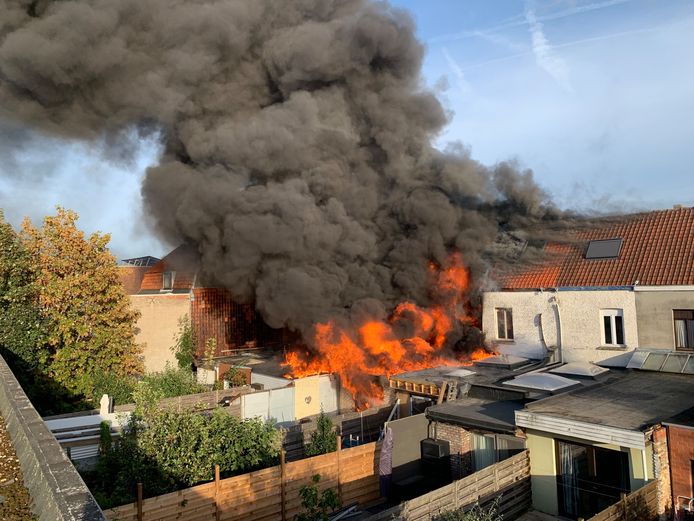 Een beeld langs de achterkant van de getroffen woningen, met hoog uitslaande vlammen en een dikke rookwolk.