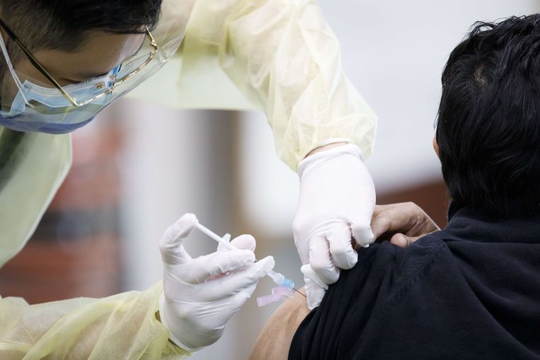 Een man krijgt een covid-vaccin toegediend. Beeld AFP