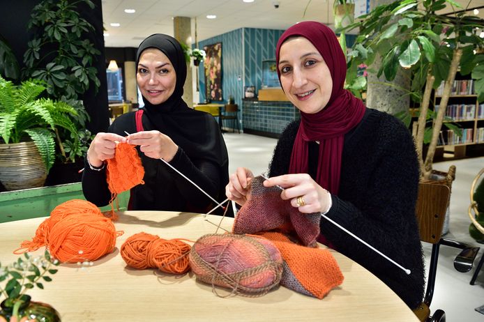 Hanan en Yasmin breien sjaals voor Koningsdag. Ze verkopen hun breisels die dag in een stand op De Raam.