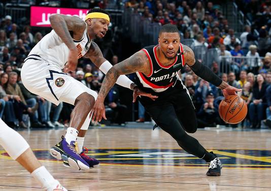 Portland Trail Blazers-guard Damian Lillard glipt voorbij Denver Nuggets’ Torrey Craig.