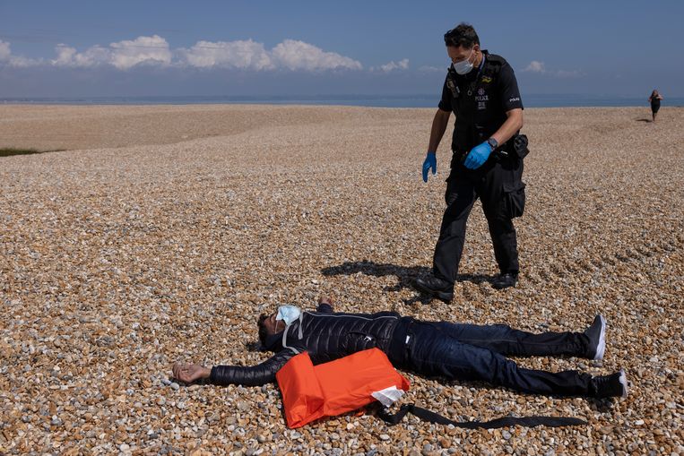 Een Britse politieman onderzoekt hoe een migrant eraan toe is, een van de veertig die door de reddingsbrigade van zee zijn gehaald en afgezet op het strand bij Dungeness.  Beeld Dan Kitwood/Getty