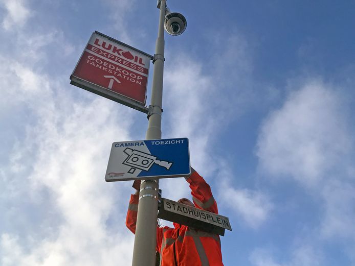 Het informatiebord over cameratoezicht op het Stadhuisplein wordt opgehangen.