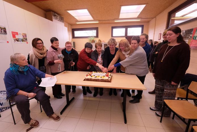 Bezoekers en medewerkers snijden de taart aan voor 20 jaar Kameleon.