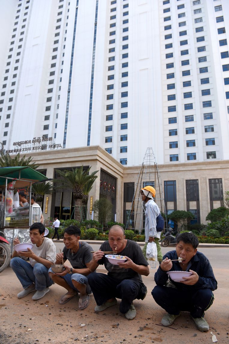 Chinese arbeiders eten hun lunch buiten op een van de straten van Sihanoukville. Beeld AFP