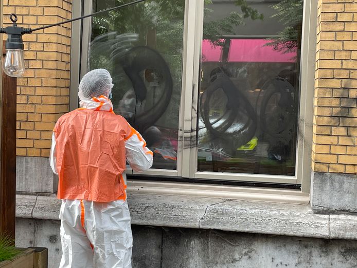 Een specialist van de politie neemt sporen van de opschriften op de ramen van het pannenkoekenhuis Stacks.