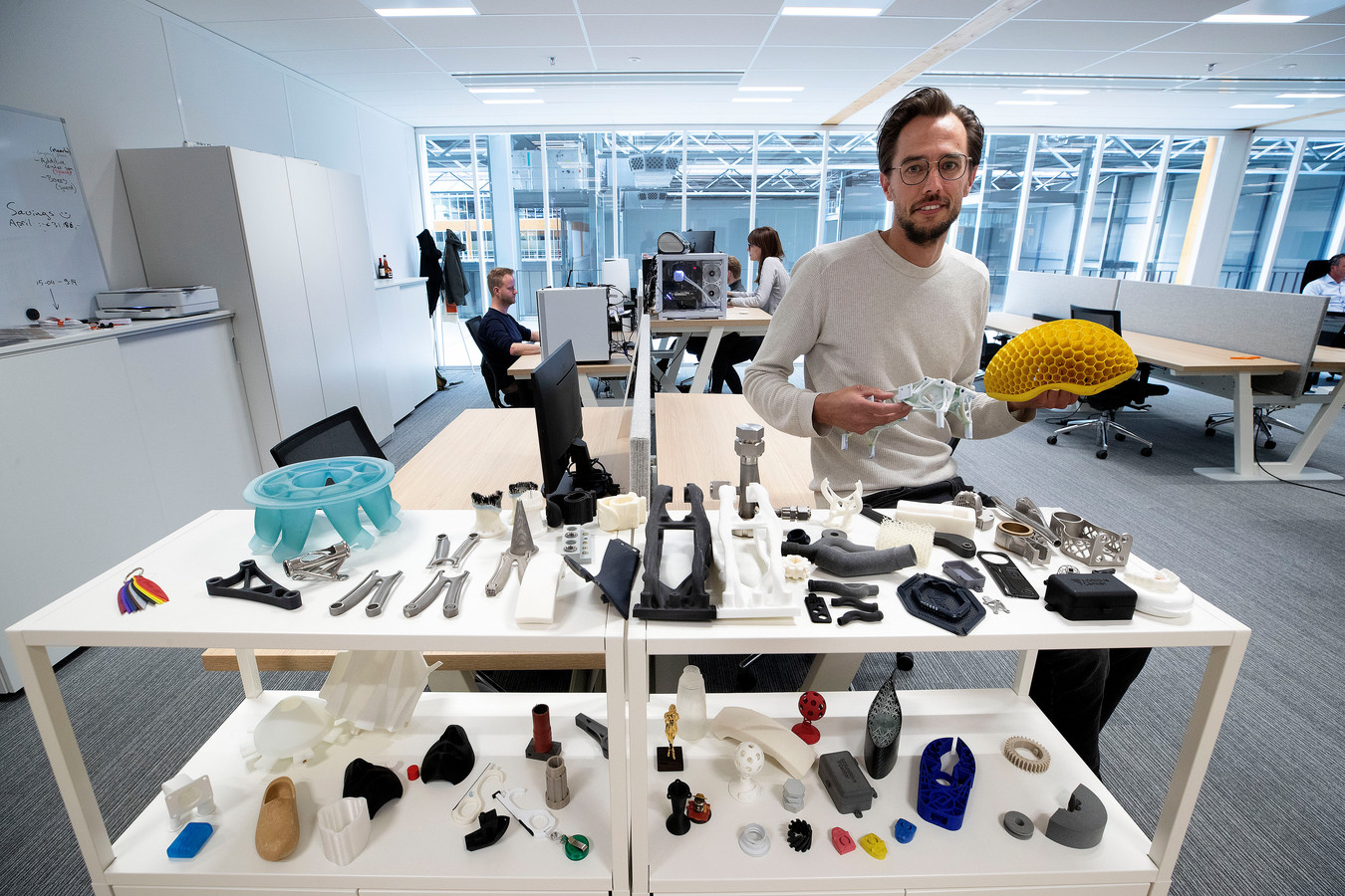 Maarten van Dijk, oprichter en ceo van Additive Center, toont enkele 3D geprinte objecten zoals de gele fietshelm.