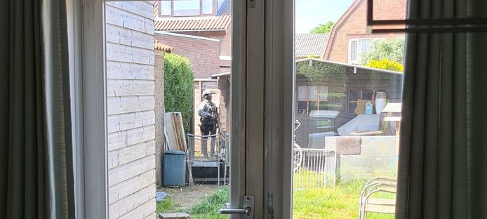 Een agent van een arrestatieteam staat in de tuin van een woning in de Treubstraat in Nijmegen na een schietpartij bij winkelcentrum Hatert.