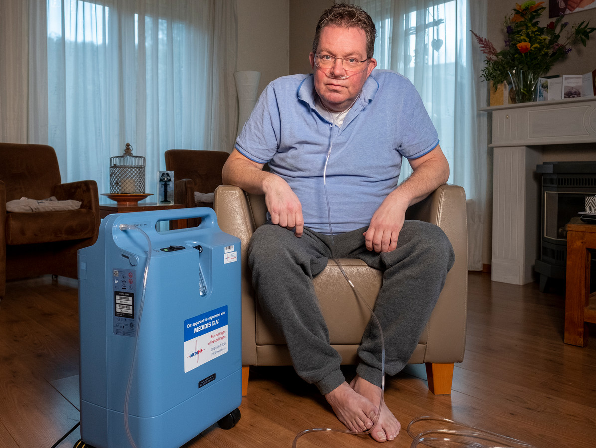Coronapatiënt Gert Palm zit in zijn woonkamer in Heerde aan een zuurstofapparaat.