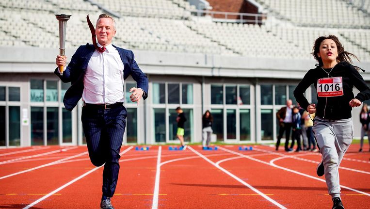 Wethouder Eric van der Burg (Sport) strijdt in 2016 met scholieren om een baanrecord op de pas gerenoveerde atletiekbaan van het Olympisch Stadion. Beeld anp