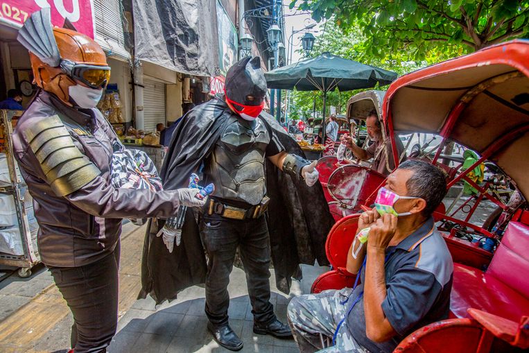 Een burger draagt een superheld Batman-kostuum en geeft gratis maskers aan bewoners in Solo City, Inonesië. Beeld Getty Images