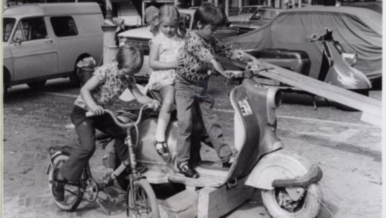 Kinderen spelen op fietsje en een scooterwrak op de Egelantiersstraat Beeld Stadsarchief