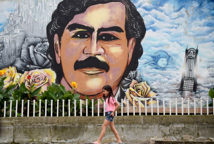 Een Colombiaans meisje loopt langs een muurschildering van drugsbaas Pablo Escobar in Medellín.
