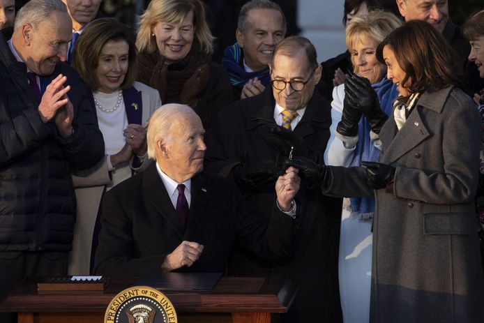 De Amerikaanse president Joe Biden geeft de pen door aan vicepresident Kamala Harris tijdens de ondertekeningsceremonie. (13/12/22)