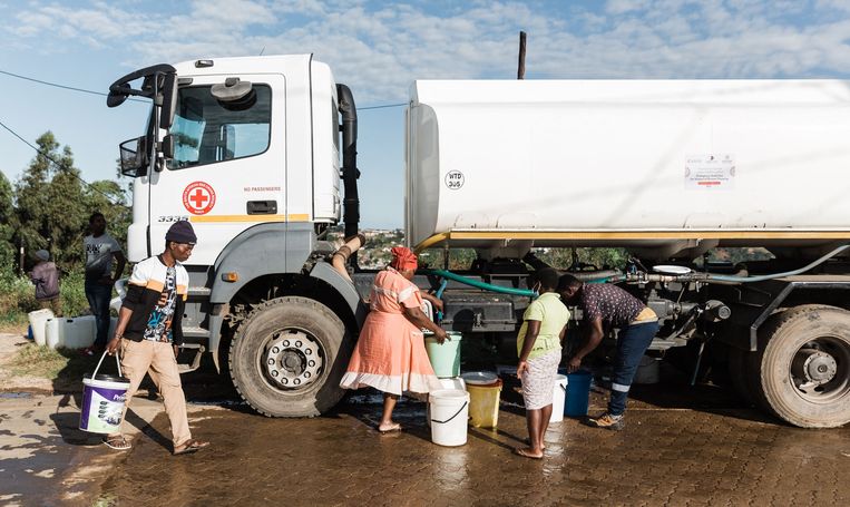 Bewoners van de sloppenwijk Mhlaseni in Verulam, ten noorden van Durban, krijgen water uit een tankwagen, omdat er geen drinkwater meer door waterleidingen stroomt na de enorme overstromingen.  Beeld AFP