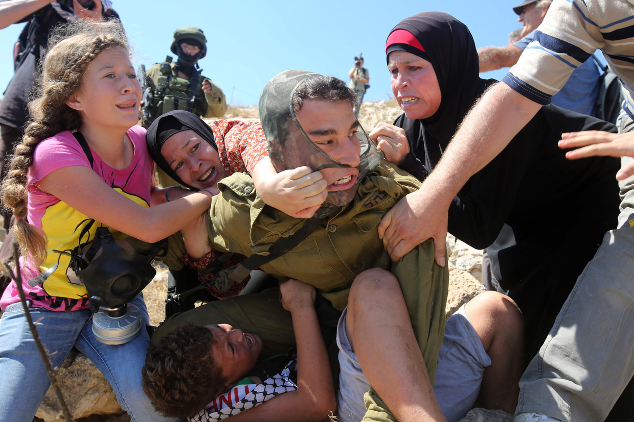 Op deze foto uit 2015 probeert Ahed Tamimi (links) met familieleden een Palestijnse jongen (onder) te bevrijden, terwijl die wordt vastgehouden door een Israëlische soldaat. Beeld AFP
