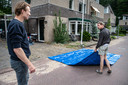 Iwan Fransen is bezig met het installeren van een watertank met pomp die het regenwater opvangt.