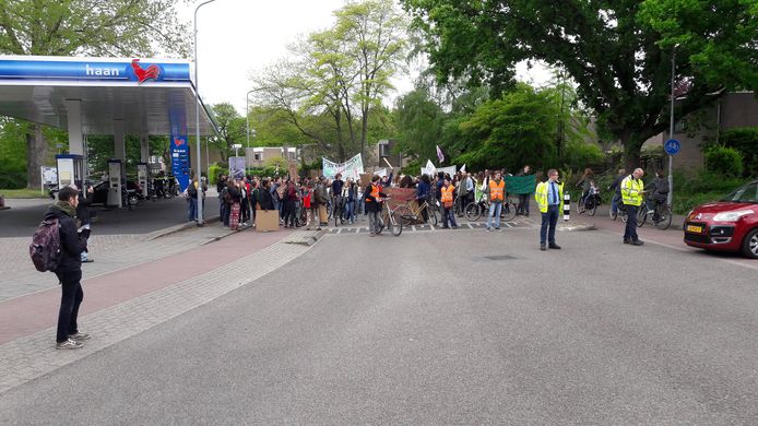 De stoet wacht op een bus die er langs moet.