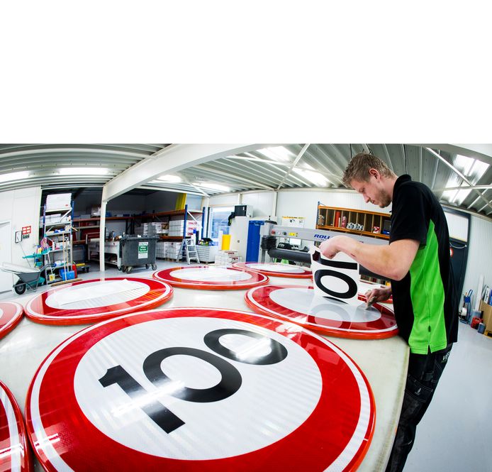 Bij Visser print & sign in Assen worden nieuwe verkeersborden voor de maximale snelheid 100 km per uur beplakt.