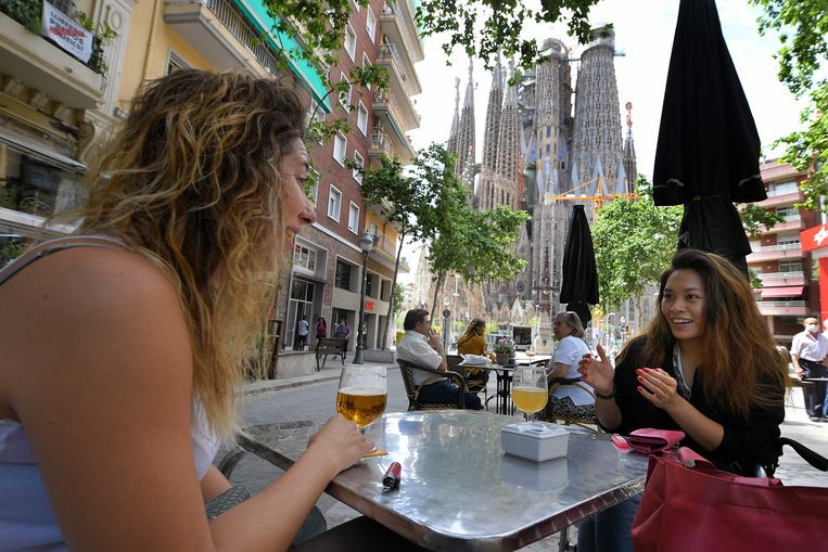 Inwoners van Barcelona genieten van een terrasje in de schaduw van de Sagrada Familia.  Beeld AFP