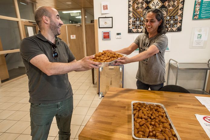 Younes Nahnahi (l) levert tulumba af aan de receptie van Huize Raffy voor het Suikerfeest.